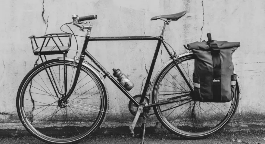 Svart cykel med korg fram och väska bak, redo att montera pakethållare för äventyr.