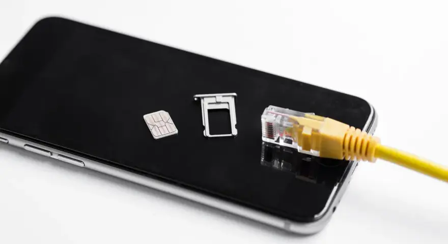 Smartfon z kartą SIM i tacką, podłączony żółtym kablem sieciowym. Możliwość play multisim.