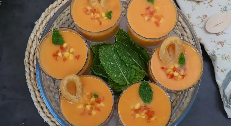 Gazpacho de mango en vasos con trocitos de mango, menta y picos.