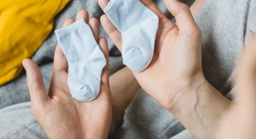 Dwie maleńkie, błękitne skarpetki w dłoniach. Zastanawiasz się, jaki rozmiar skarpetek dla noworodka będzie najlepszy?