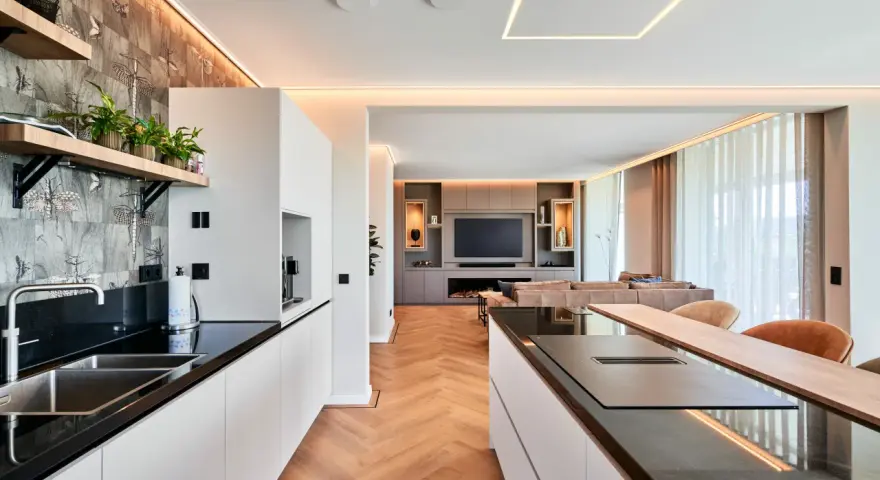 Moderne Küche mit Kochinsel und Wohnbereich. Die indirekte Beleuchtung unterstreicht die Eleganz. Informieren Sie sich über spanndecke kosten für Ihr Zuhause.