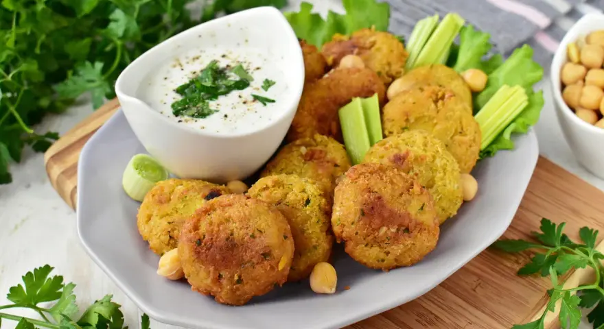 Pyszny falafel przepis na talerzu, podany z sosem jogurtowym, selerem i natką pietruszki. Idealna przekąska!