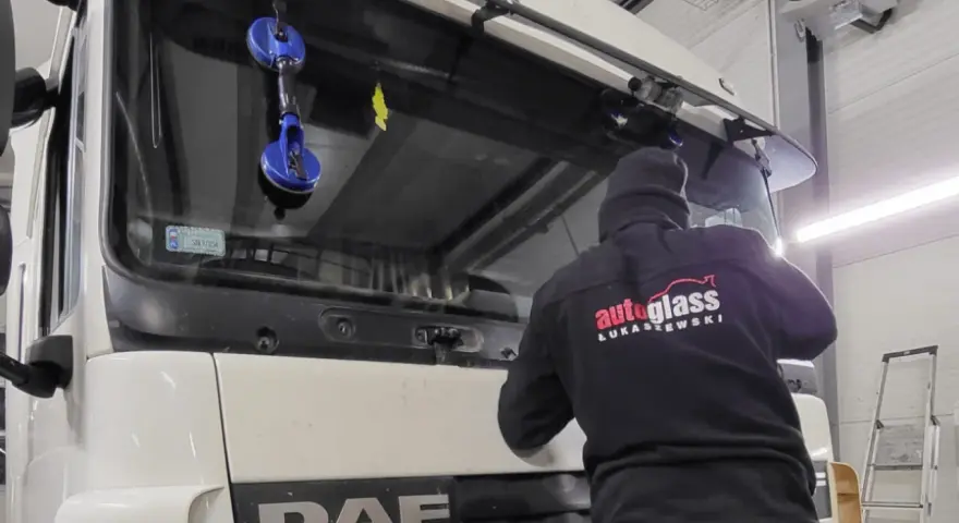Montaż szyby w traktorze DAF. Pracownik firmy "Autoglass Łukaszewski" używa przyssawek do bezpiecznego osadzenia nowej szyby.