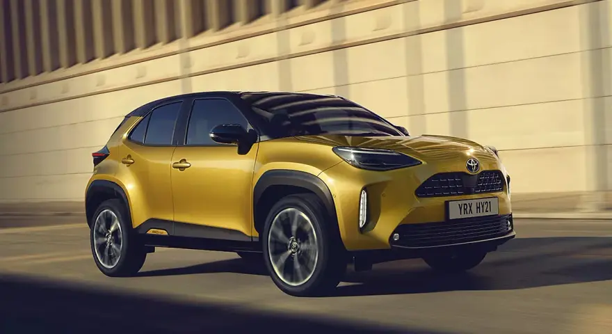Złoty Toyota Yaris Cross Hybrid w ruchu. Dowiedz się, ile kosztuje Toyota Yaris Hybrid i odkryj jego zalety.