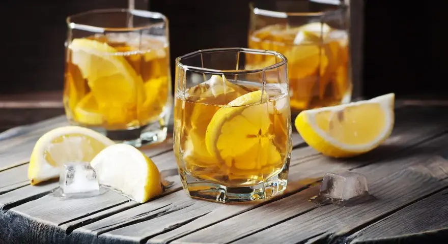 Trzy szklanki z bursztynowym napojem i plasterkami cytryny. Czy to metaxa, co to za drink?