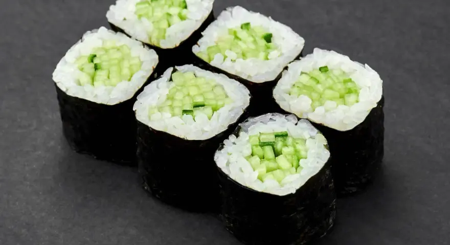Sześć kawałków sushi z ogórkiem, ułożonych na ciemnym tle.