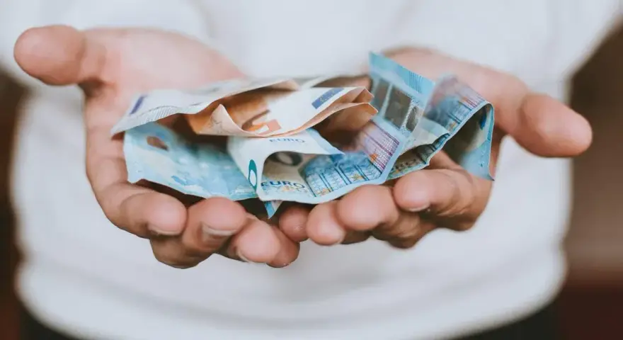 Hände halten zerknitterte Euro-Scheine. Das Geld ist für das geplante **auslandsjahr 3 monate** gedacht.