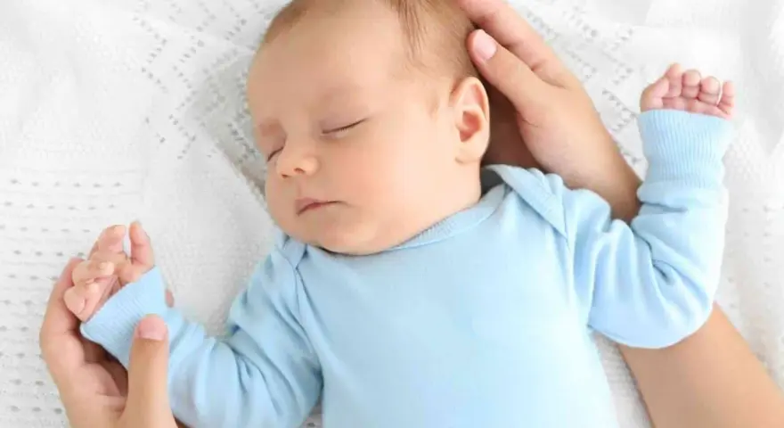 Un neonato dorme sereno sul petto della mamma, cullato dalle sue mani.