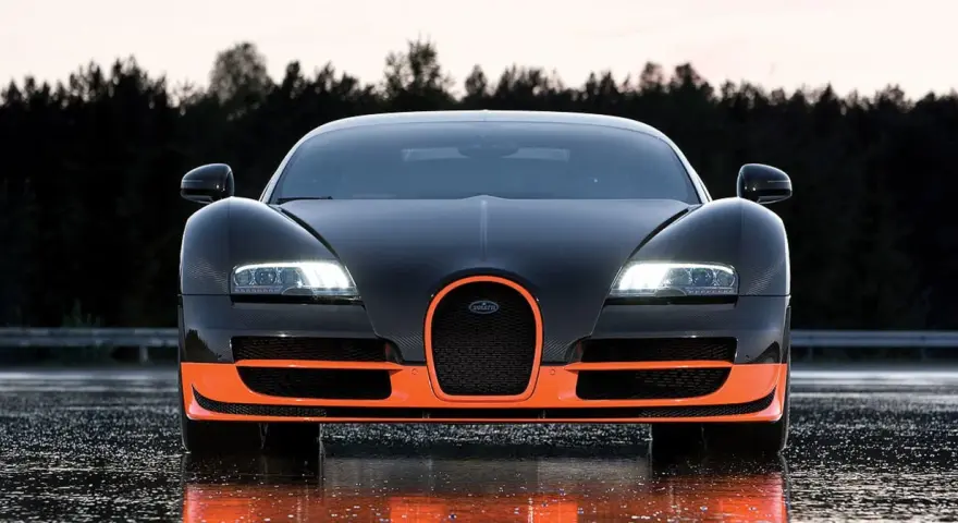 Czarny Bugatti Veyron z pomarańczowymi akcentami, gotowy do jazdy po mokrej nawierzchni.