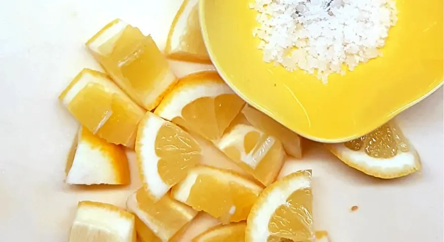 Frische Zitronenspalten und grobes Salz in einer gelben Schale – die perfekte Basis für viele Rezepte mit Zitrone.