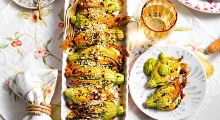 Deliziosi fiori di zucca al forno, ripieni e dorati, serviti su un piatto con un tocco di verde.