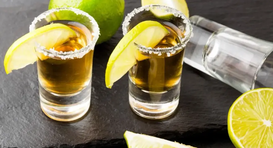 Dwa kieliszki tequili z solą i limonką, gotowe do degustacji. Czas sprawdzić, jak smakuje tequila!