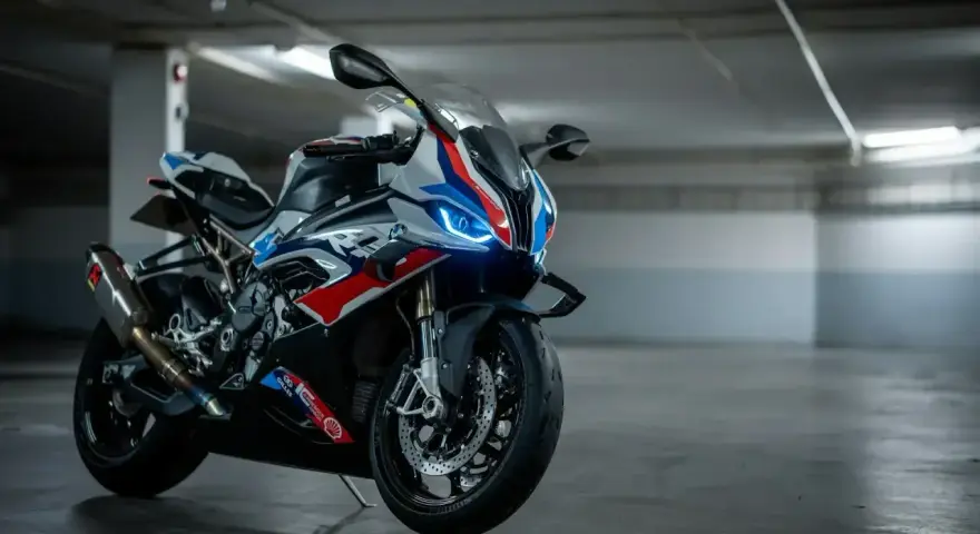Sportowy motocykl BMW XR w barwach M, z niebieskimi światłami LED, gotowy do jazdy po torze.