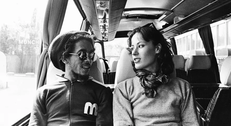 Bob Marley i Kate Marley w autobusie, patrzą na siebie z uśmiechem.
