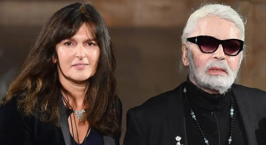 Karl Lagerfeld, iconico stilista Chanel, con una donna dai capelli scuri e un sorriso discreto.