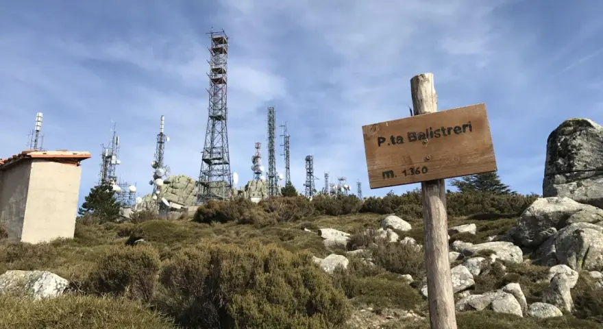 Segnale in legno a Punta Balistreri, m. 1360, con torri di telecomunicazioni sullo sfondo.