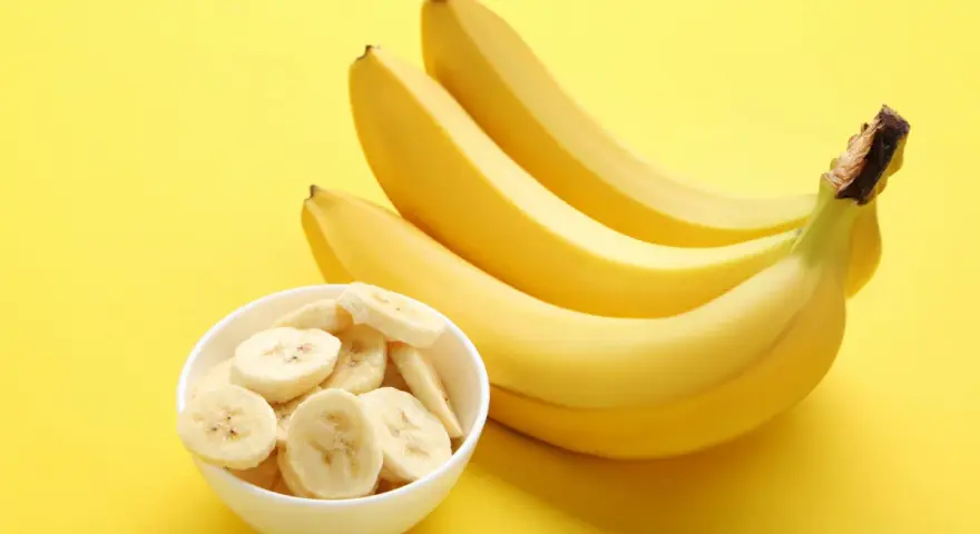Kilka żółtych bananów i miseczka pokrojonych plasterków. Poznaj banan wartości odżywcze i ciesz się zdrową przekąską!