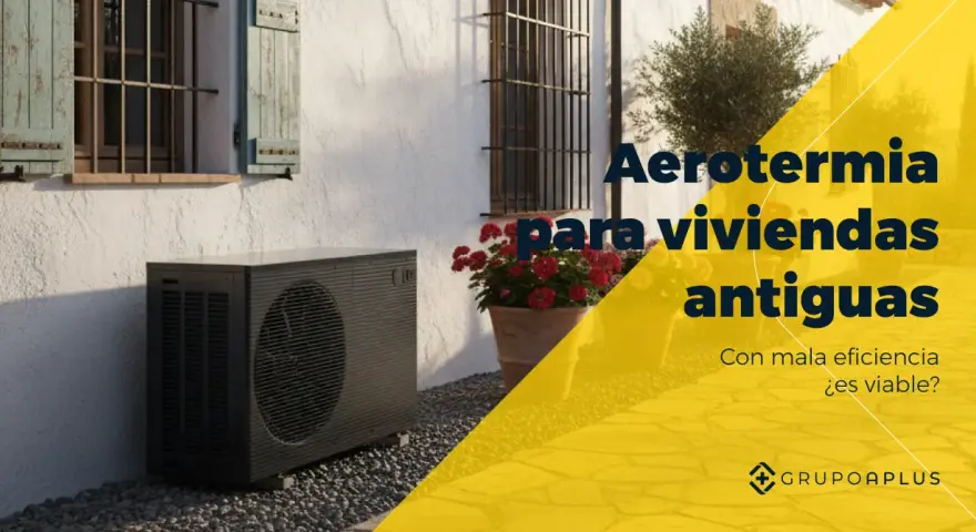 Unidad exterior de bomba de calor aire-agua junto a una casa antigua con flores. Aerotermia para viviendas antiguas.