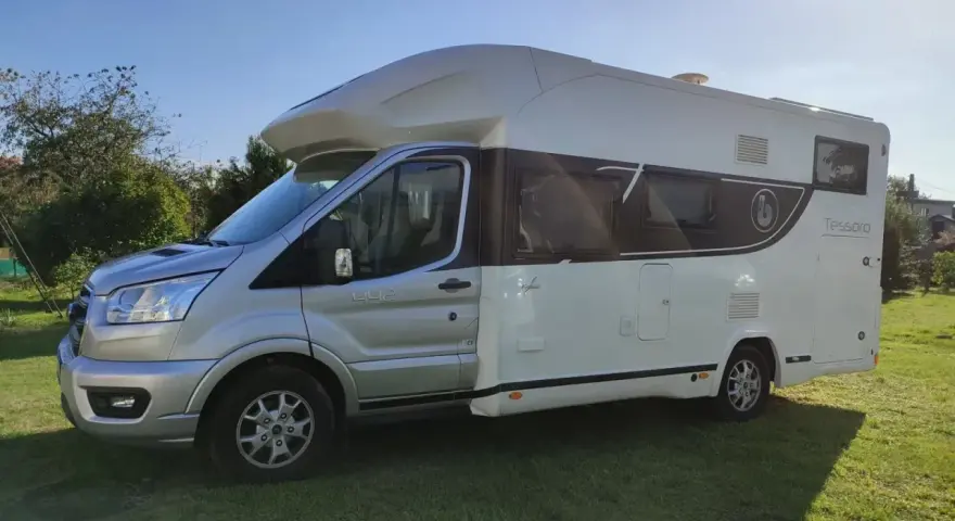Kamper Benimar Tessoro 442 na zielonej trawie, gotowy na przygodę.