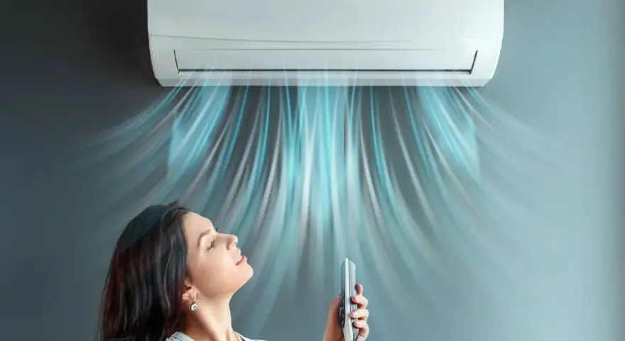 Donna rilassata sotto l'aria fresca di un climatizzatore inverter, che ne spiega il significato di comfort e risparmio energetico.