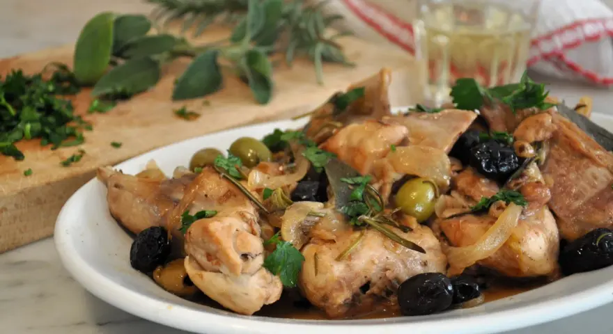 Piatto di coniglio alla cacciatora in bianco, con olive, cipolle e rosmarino. Un classico della cucina italiana.