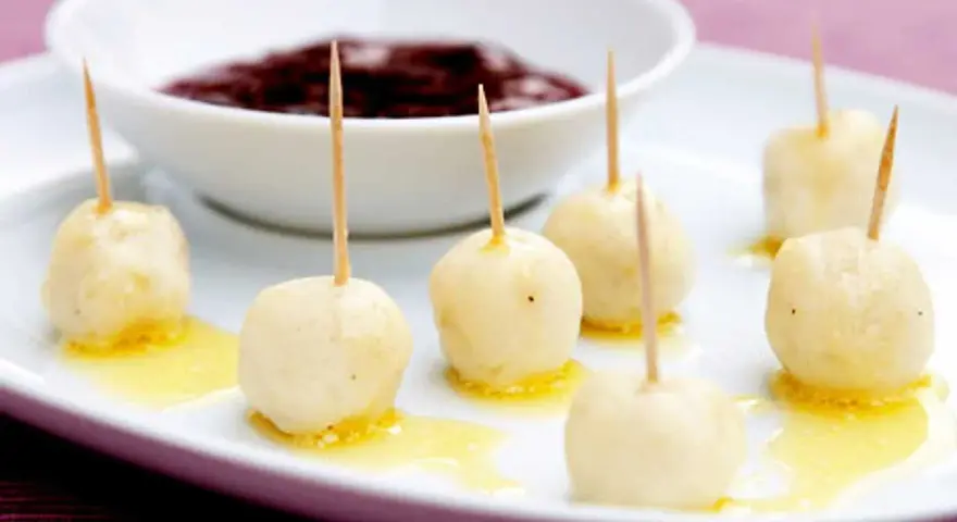 Små, gyllene kroppkakor med tandpetare, serverade med en skål mörk sylt. Ett spännande recept att prova!