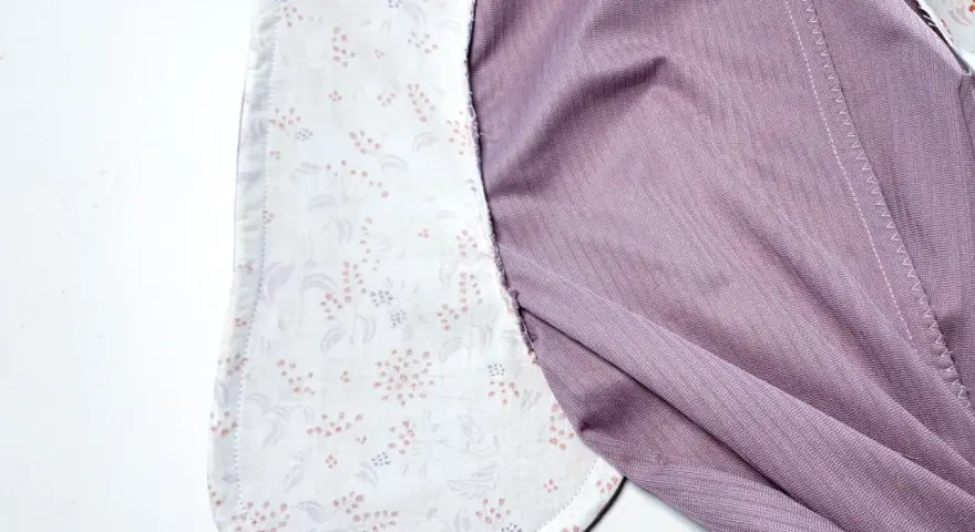 Détail d'un vêtement en cours de confection, montrant la doublure à motifs floraux des poches italiennes et le tissu extérieur violet.