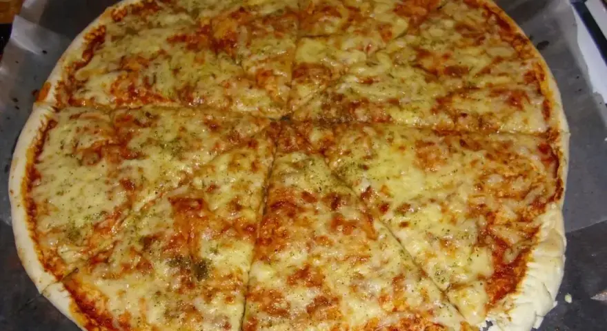Pyszna, gorąca margerita z ciągnącym się serem i aromatycznymi ziołami, pokrojona na 8 kawałków.