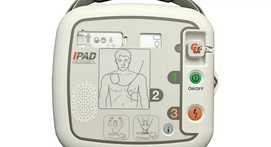 Automatyczny defibrylator zewnętrzny (AED) iPAD w kolorze białym, z widocznymi przyciskami i instrukcjami.