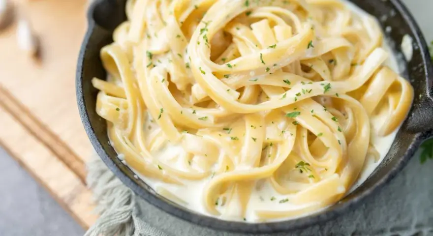 Fettuccine crémeux enrobé d'une onctueuse sauce fromage blanc, parsemé de persil frais. Un délice réconfortant.