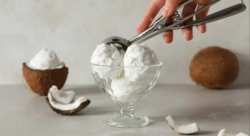 Copa de cremoso helado de coco, con trozos de coco fresco alrededor. ¡Un postre tropical!
