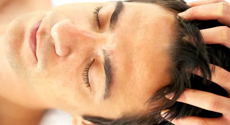 Fingers gently work through dark hair, demonstrating how to massage scalp for relaxation and hair health.