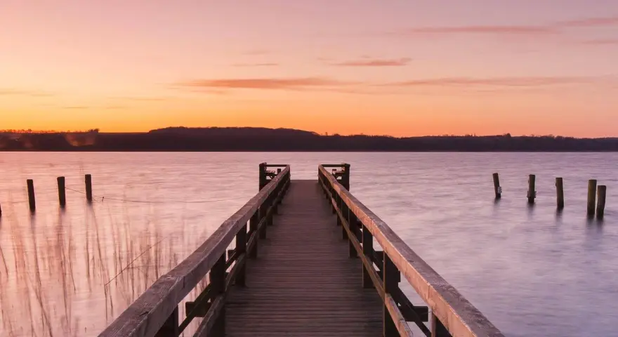 Holzsteg am See bei Sonnenuntergang, ein idyllischer Ort für Badeseen Schleswig-Holstein.