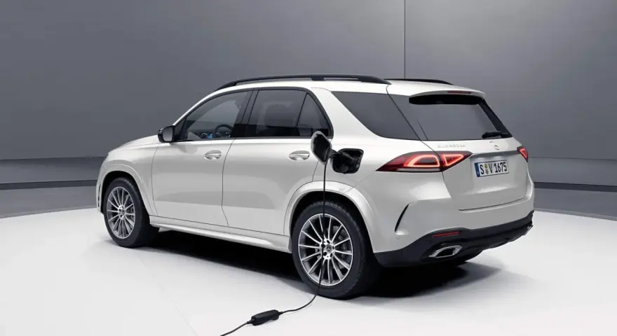 Biały samochód hybrydowy Mercedes-Benz GLE jest ładowany.