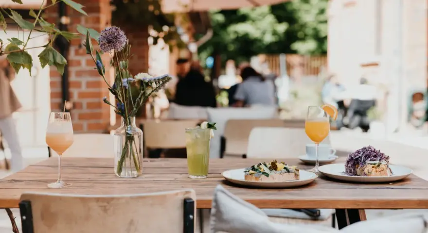 Leckeres Frühstück im 21 gramm Berlin: Toast mit Belag, Drinks & Blumen auf Holztisch.