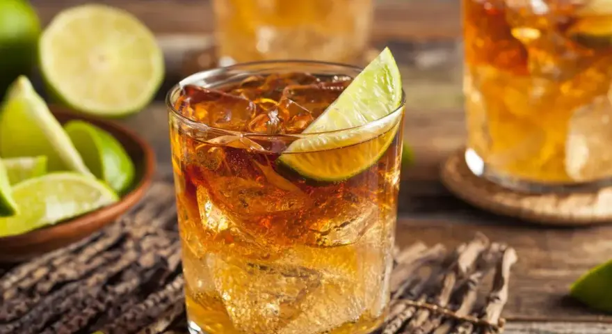 Idealny drink z rumem: orzeźwiający rum z lodem i limonką, obok miseczka z ćwiartkami limonki.