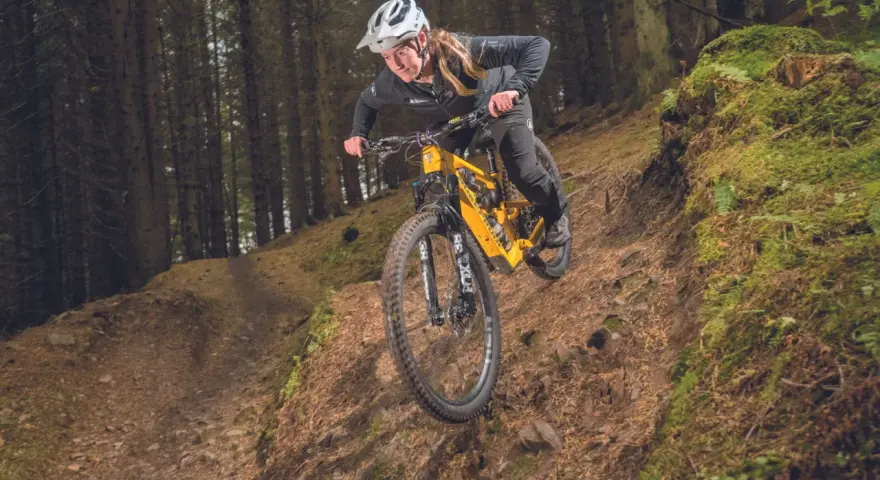 A mountain biker navigates a steep, wooded trail, showcasing the thrill of downhill mtb trails.