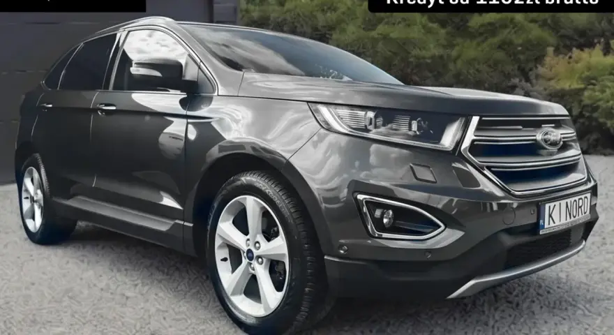 Ford Edge 2.0 TDCI w ciemnoszarym kolorze, zaparkowany przed garażem. Oferta leasingu i kredytu.