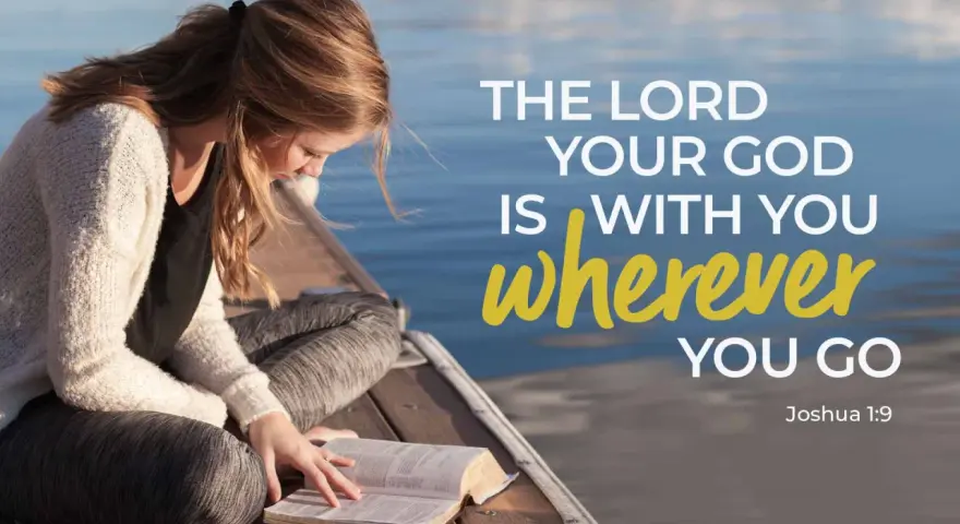 A young woman reads her Bible by the water, finding comfort in trusting God in difficult times with verses like Joshua 1:9.