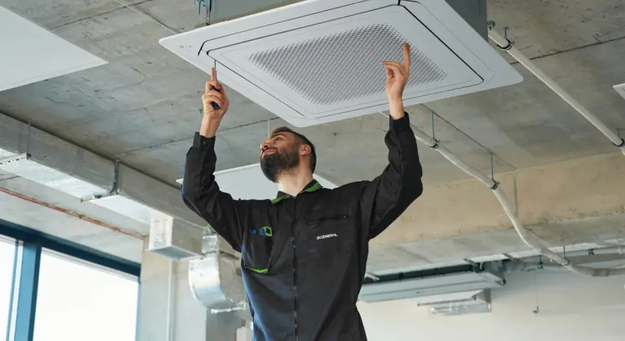 Técnico ajustando una unidad de cassette para la instalación de ventilación en un techo de hormigón.