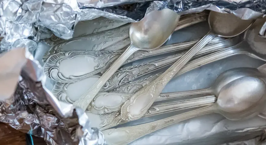 Stare, ozdobne łyżki w folii aluminiowej, gotowe do czyszczenia. Dowiedz się, jak wyczyścić srebro, by odzyskało blask.