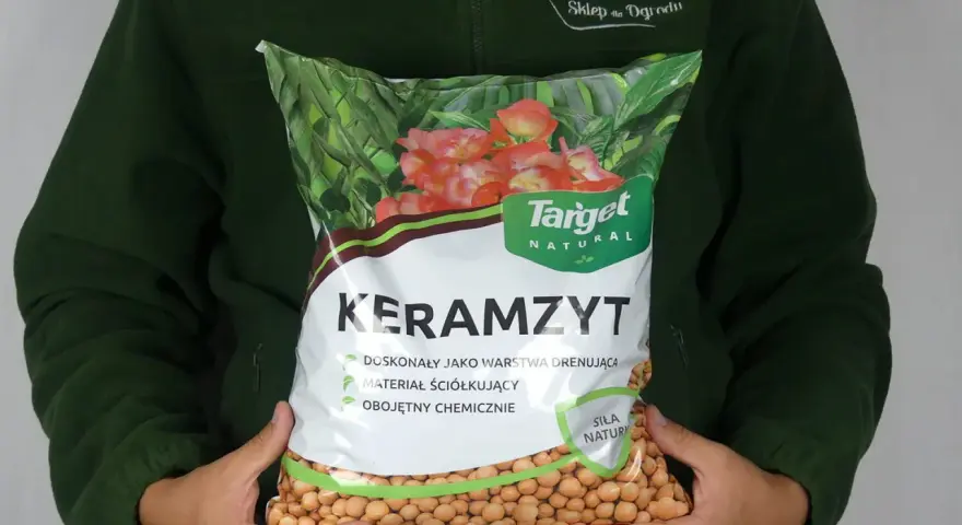 Osoba trzyma worek z napisem "Keramzyt", który jest doskonałym materiałem drenażowym i ściółkującym.