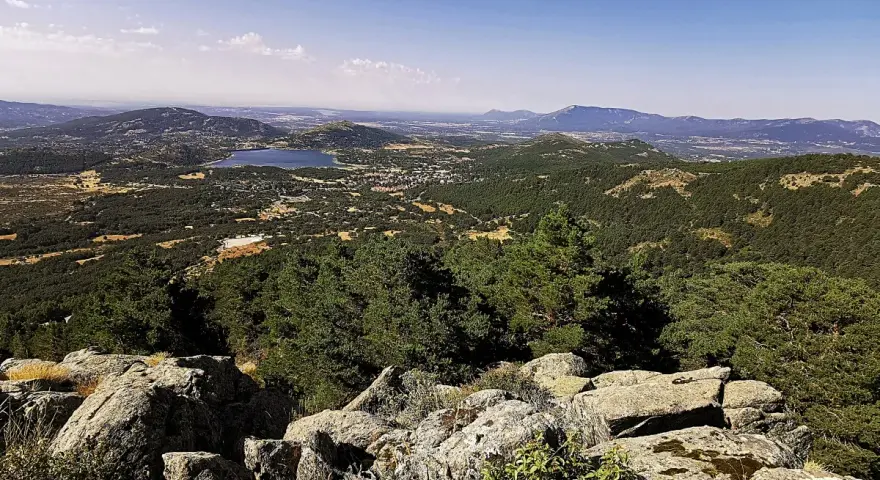 Vista panorámica del valle de la barranca, con un lago azul y montañas verdes bajo un cielo despejado.