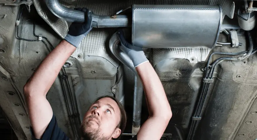 Mechanic working on a car's exhaust system. This tune up consists of replacing a section of the exhaust pipe and muffler.