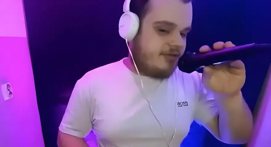 Młody dj akun w słuchawkach i białej koszulce z mikrofonem w ręku, w studiu z fioletowym oświetleniem.