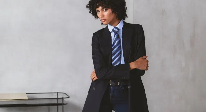 Persona androgina con traje a rayas, camisa azul y corbata a juego, posando con confianza.