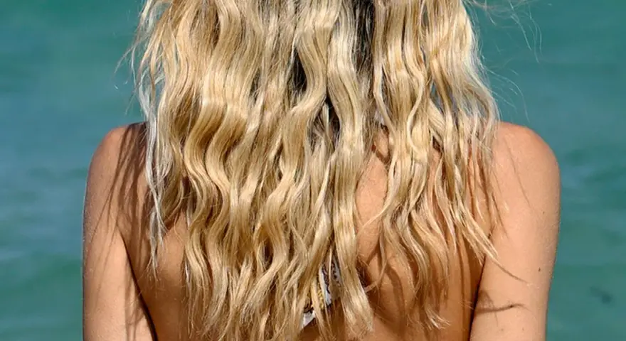 Blondes Haar mit Beach Waves im Meer. Die Sonne scheint auf die Schultern.