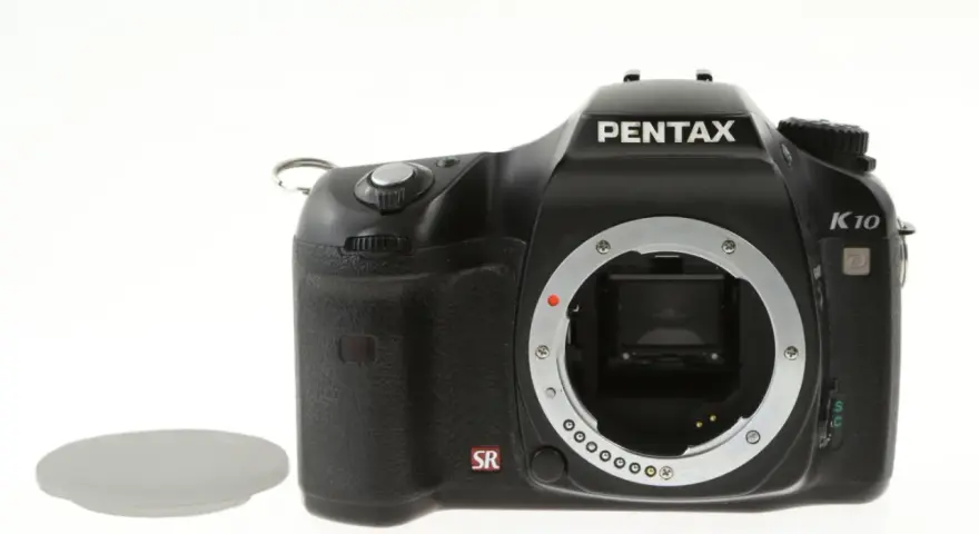 Czarny aparat Pentax K10 z widocznym mocowaniem obiektywu i osłoną. Wewnątrz widoczny jest sensor ccd.