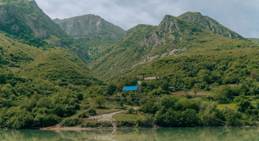 Zielone góry nad jeziorem, z domami i niebieskim dachem.