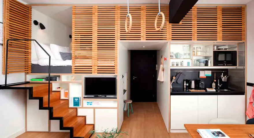 Acogedor apartamento con **dormitorios con techos altos** elevados, escaleras de madera, cocina compacta y zona de estar.
